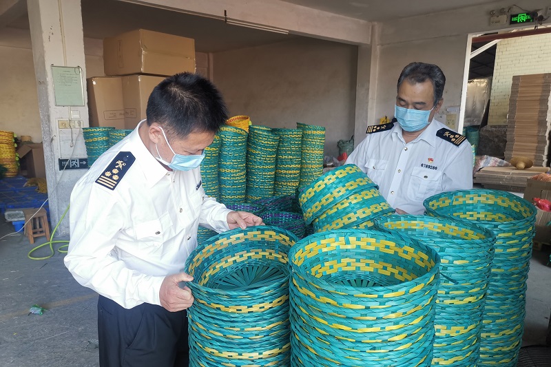 图为：海关关员指导企业做好雨季出口竹木草制品质量安全保障工作